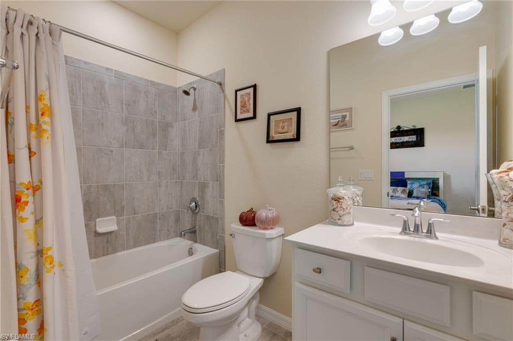 Bathroom featuring a white vanity with integrated sink, chrome faucet, and a large wall-mounted mirror