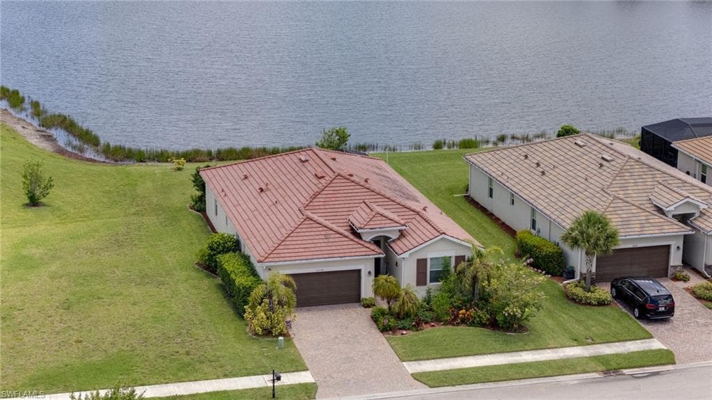 Mediterranean-style home featuring a terracotta tile roof, a paver driveway, and an attached two-car garage
