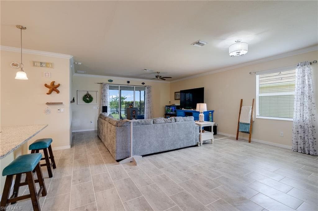 Spacious living area featuring light-toned tile flooring, recessed lighting, and a modern drum light fixture