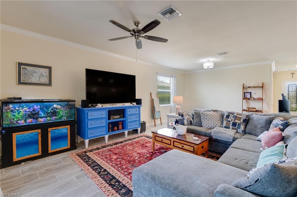 Spacious living area featuring light-toned walls, crown molding, and wood-finish flooring