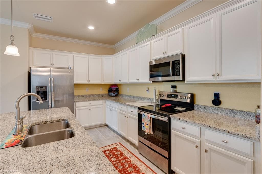 White cabinetry with stainless steel appliances, granite countertops, and a dual basin sink with a high-arc faucet