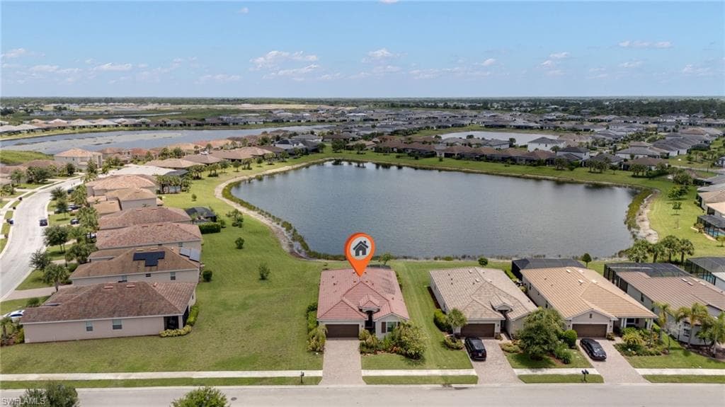 Waterfront property featuring a tiled roof, paver driveway, and a landscaped front yard