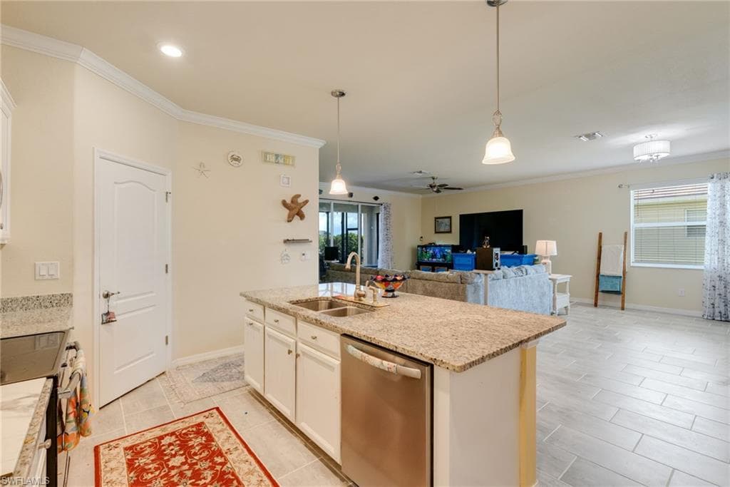 Open-concept living space featuring a kitchen island with dual sinks, light-colored cabinetry, and stainless steel appliances