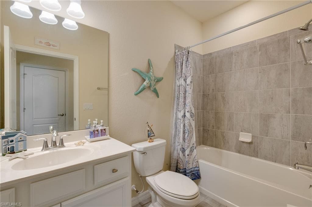 Full bathroom featuring a white vanity with integrated sink, rectangular mirror, and an overhead light fixture
