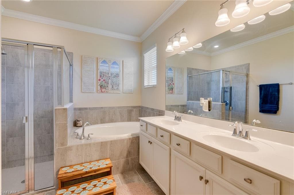 Spacious bathroom featuring a dual vanity with white cabinetry, light-toned countertops, and a wide mirror