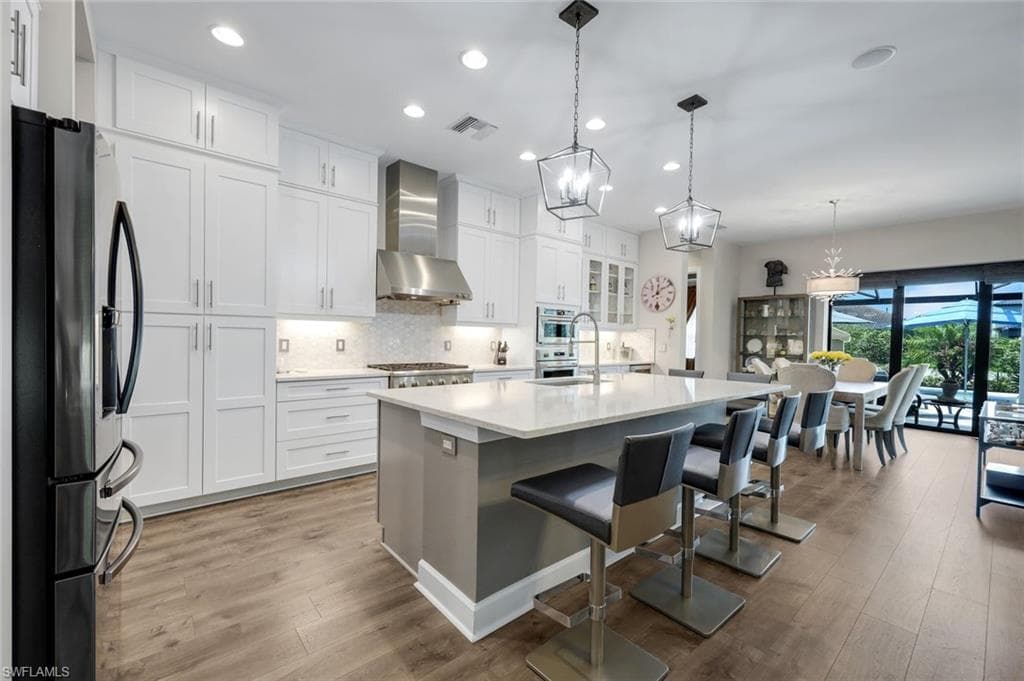 Modern kitchen featuring white cabinetry, a large center island with seating, stainless steel appliances, and wood-finish flooring