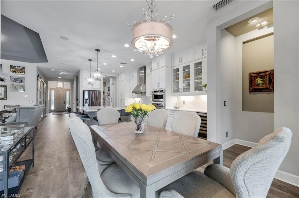 Dining area featuring wood-finish flooring, a decorative chandelier, and a substantial dining table with patterned inlay