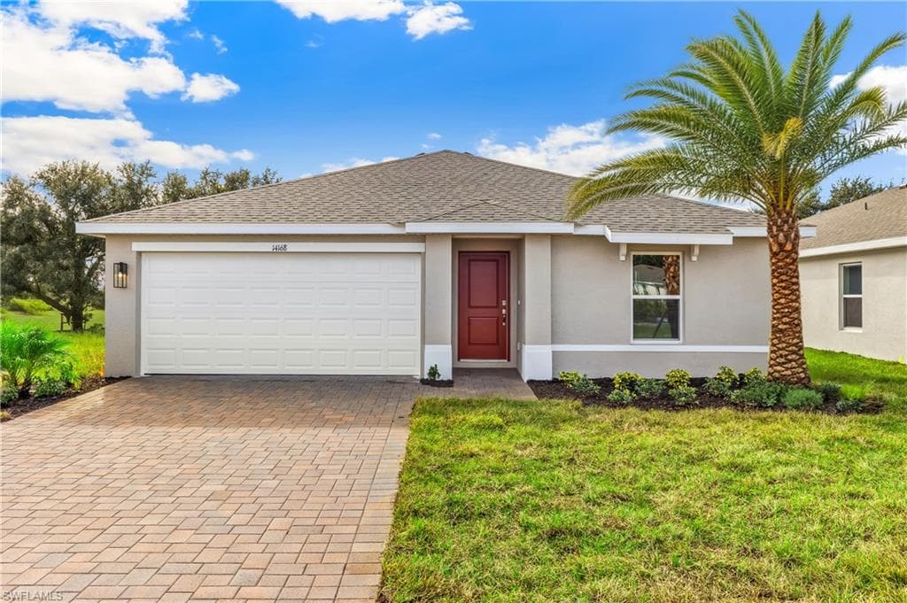 Model Home. Contemporary stucco exterior with a prominent red entry door, an attached garage, and a paver driveway