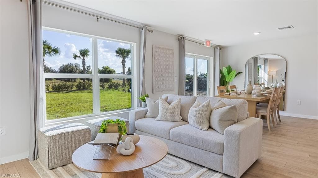 Model home. Living area with light wood-type flooring and recessed lighting
