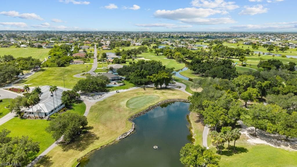 Expansive golf course property featuring a manicured green, a large water hazard, and mature trees