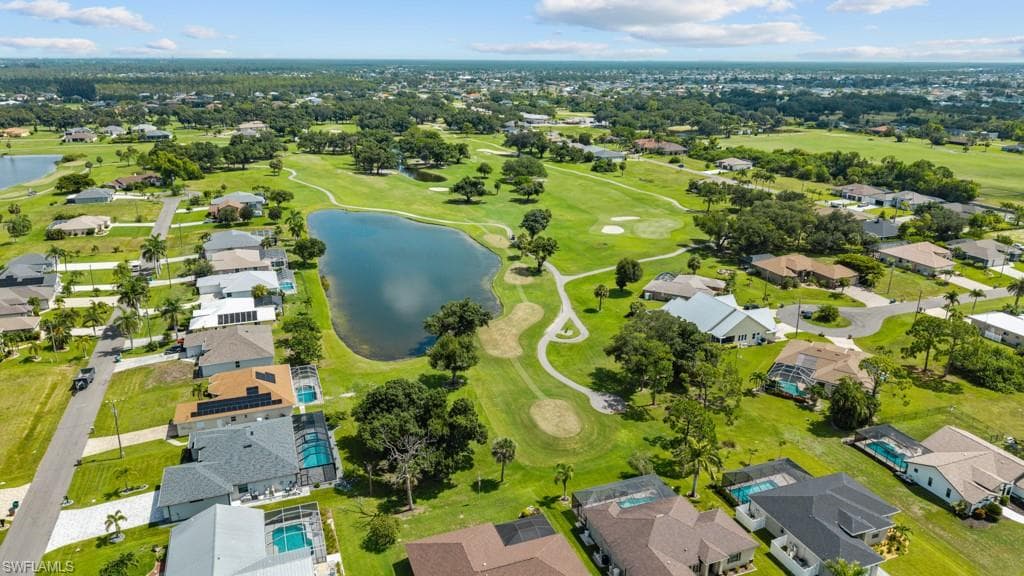 Expansive golf course setting featuring a water hazard, surrounding residential properties, paved streets, and mature trees