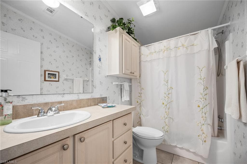 Bathroom featuring a vanity with an integrated sink, built-in cabinetry, a toilet, and a shower-over-tub combination