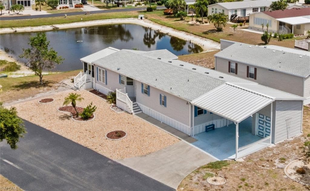 Light-colored siding home featuring a gravel front yard with mature landscaping, a covered carport, and an adjacent storage shed