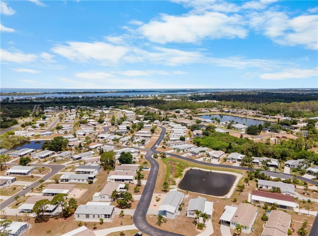 Aerial perspective showcasing a residential community with multiple homes, roadways, and three distinct water features