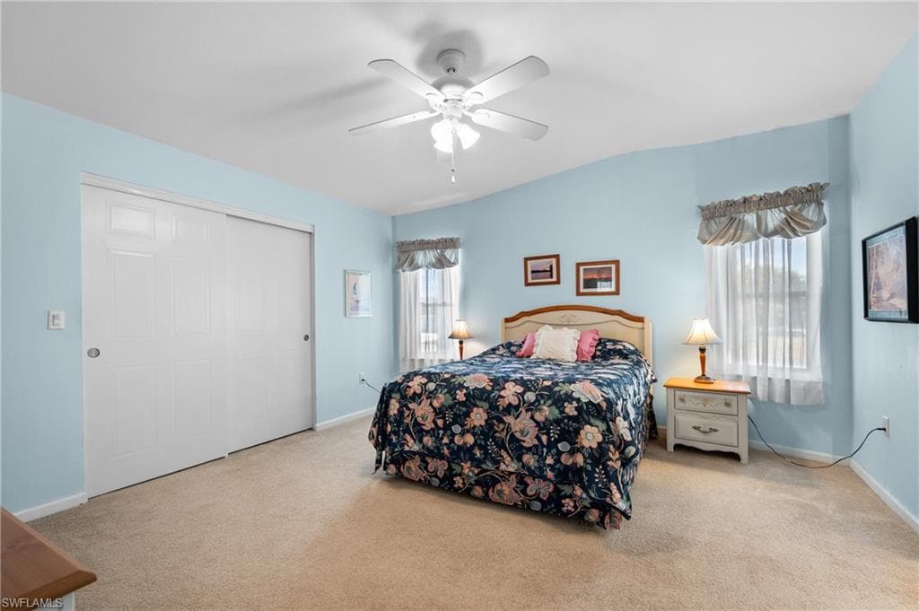 Carpeted room featuring a vaulted ceiling and a ceiling fan with light fixture