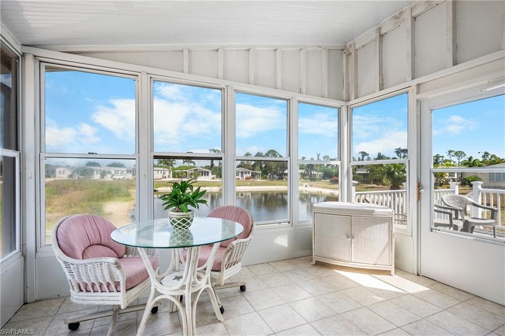 Enclosed porch featuring ceramic tile flooring, multiple windows, a corner built-in cabinet, and an exterior door leading to a deck