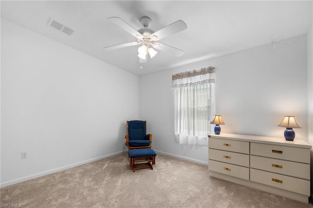Neutral wall paint with carpet flooring, a ceiling fan, and a window with sheer curtains
