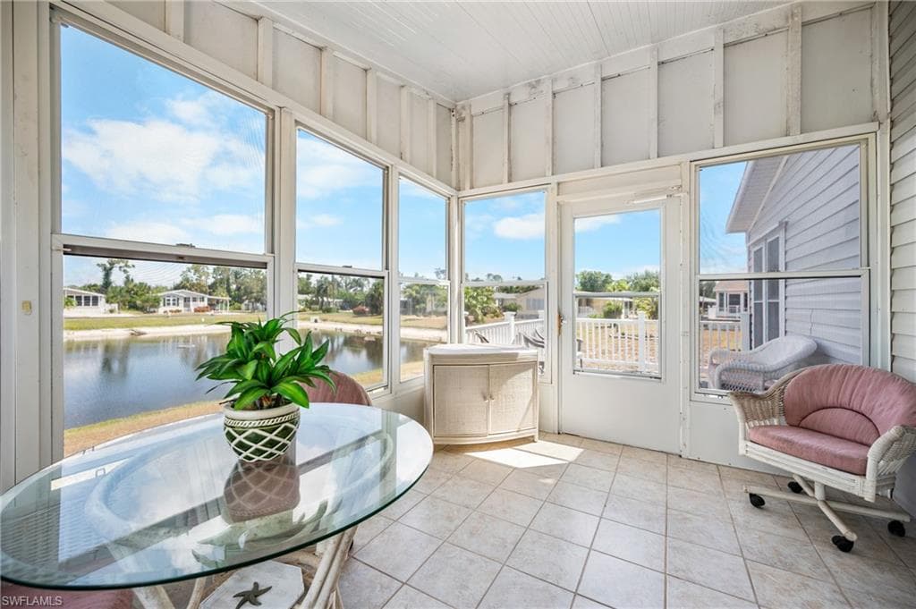 Enclosed patio featuring floor-to-ceiling windows, white paneled walls, a single exterior door, and light-toned tile flooring