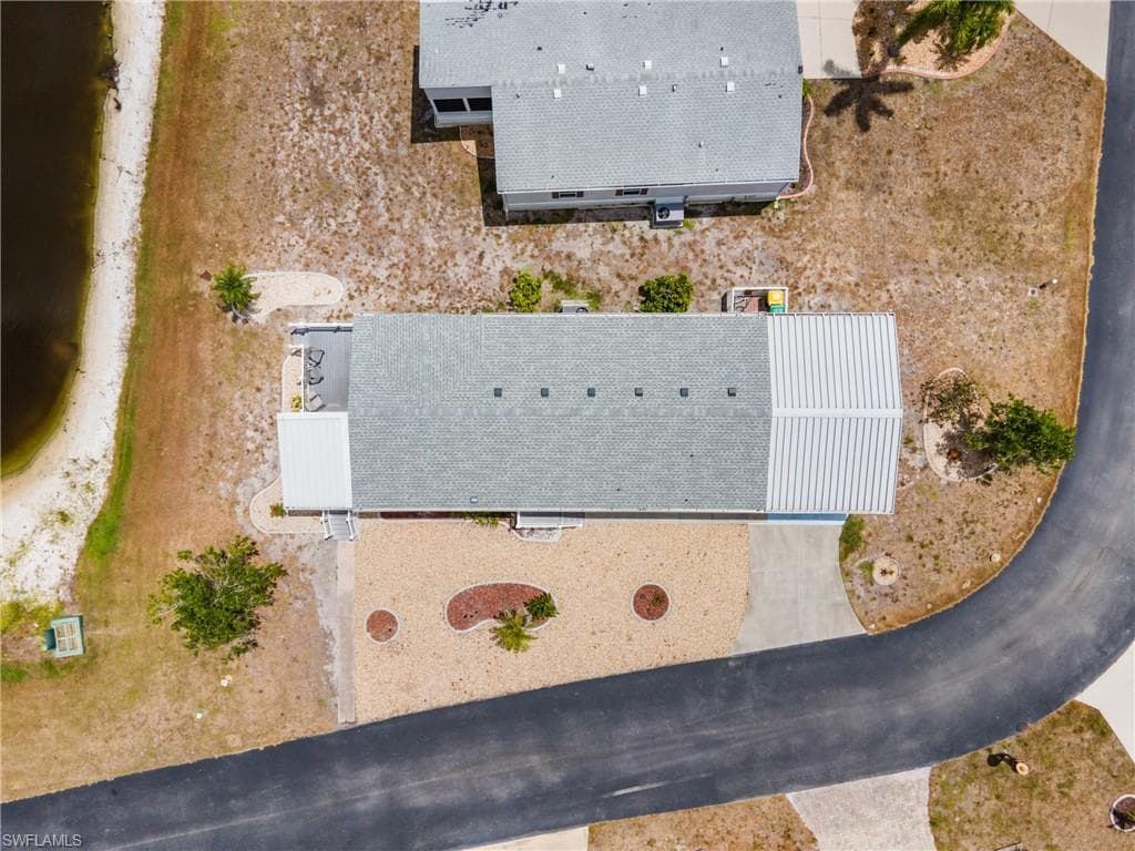 Property featuring a shingle and metal roof combination, paved driveway, and gravel landscaping