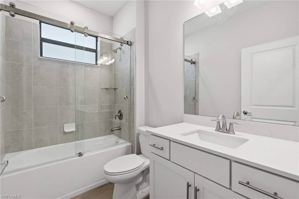 Bathroom featuring a white vanity with an integrated sink, brushed nickel fixtures, and a large mirror