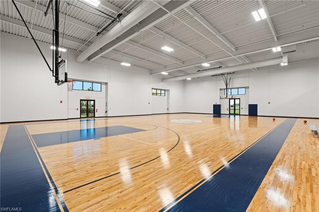 Indoor basketball court with polished wood flooring, two basketball hoops, high ceilings, and recessed lighting