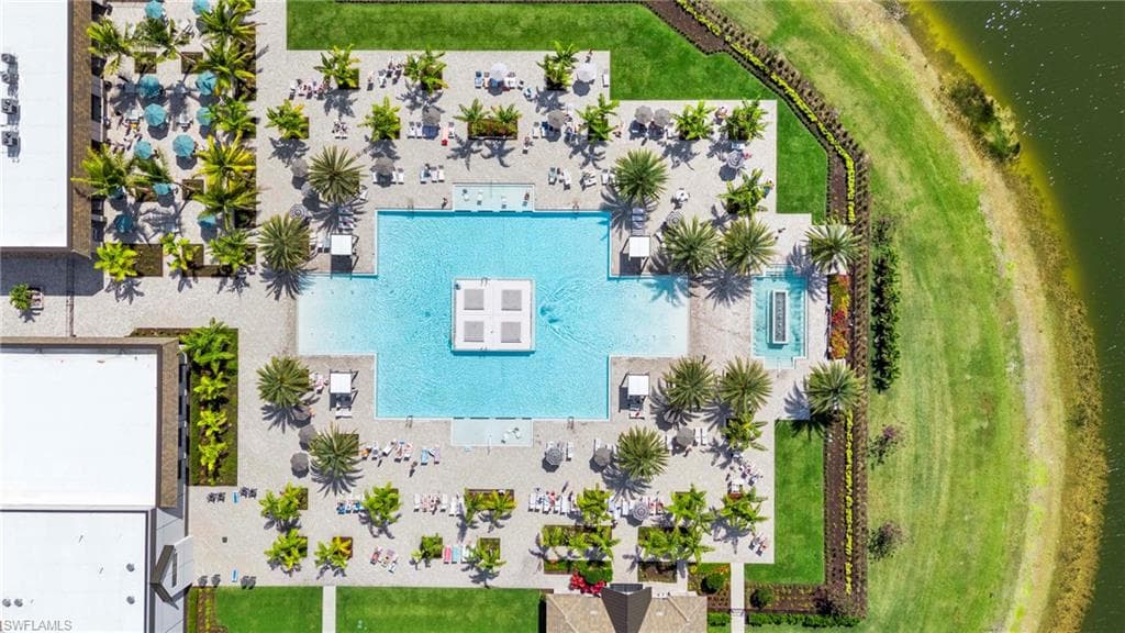 Expansive outdoor amenity area featuring a large swimming pool, surrounding lounge seating, mature palm trees, and a decorative water feature