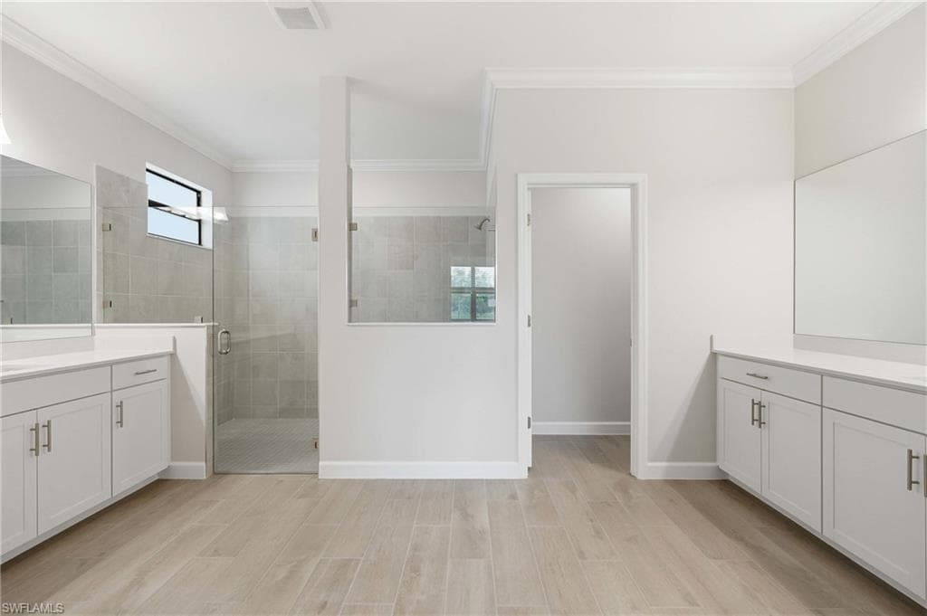 Dual vanity bathroom featuring wood-finish tile flooring and a glass-enclosed shower with tiled walls