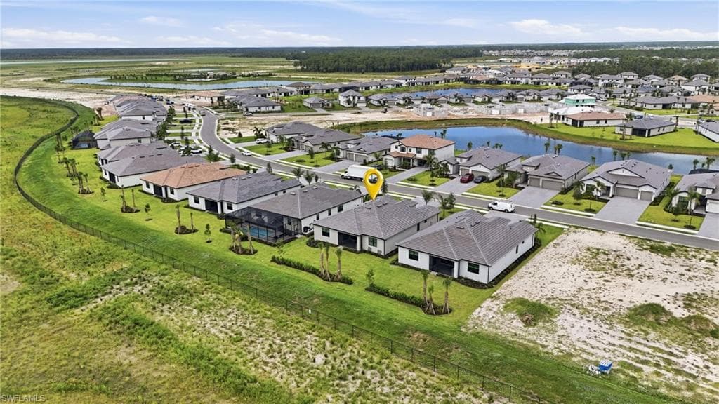 Aerial view of a residential community featuring single-story homes with dark shingle roofs, paved driveways, and manicured lawns