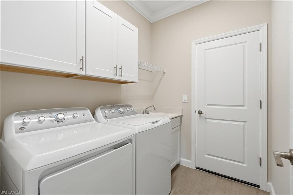 Dedicated laundry space featuring white cabinetry, a built-in sink with a chrome faucet, and plank-style tile flooring