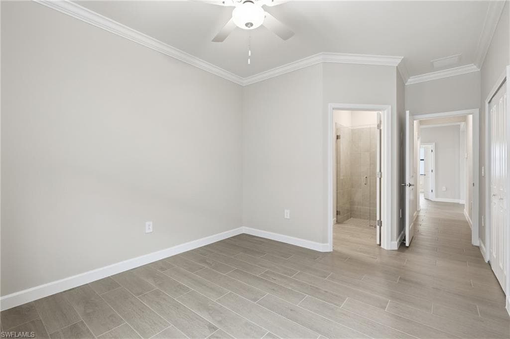Interior space featuring light gray walls, wood-finish tile flooring, crown molding, and a ceiling fan