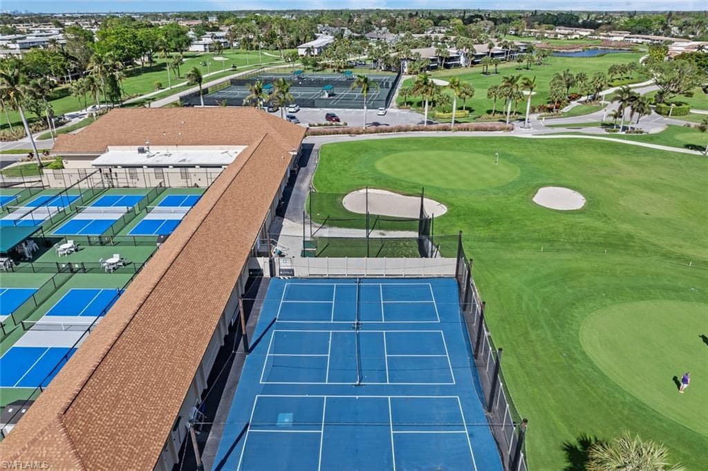 Expansive property featuring multiple blue-surfaced pickleball courts, a large blue-surfaced tennis court, and a meticulously maintained golf course with sand traps