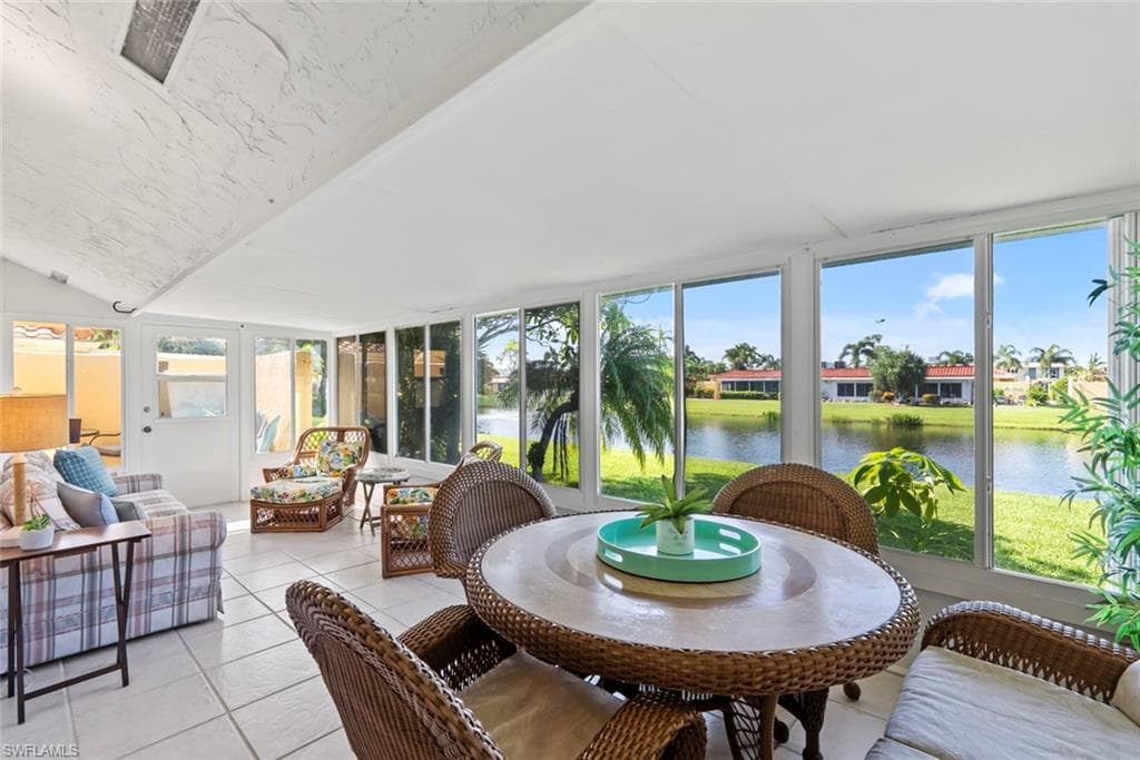 Expansive sunroom featuring floor-to-ceiling windows, ceramic tile flooring, and a panoramic water backdrop