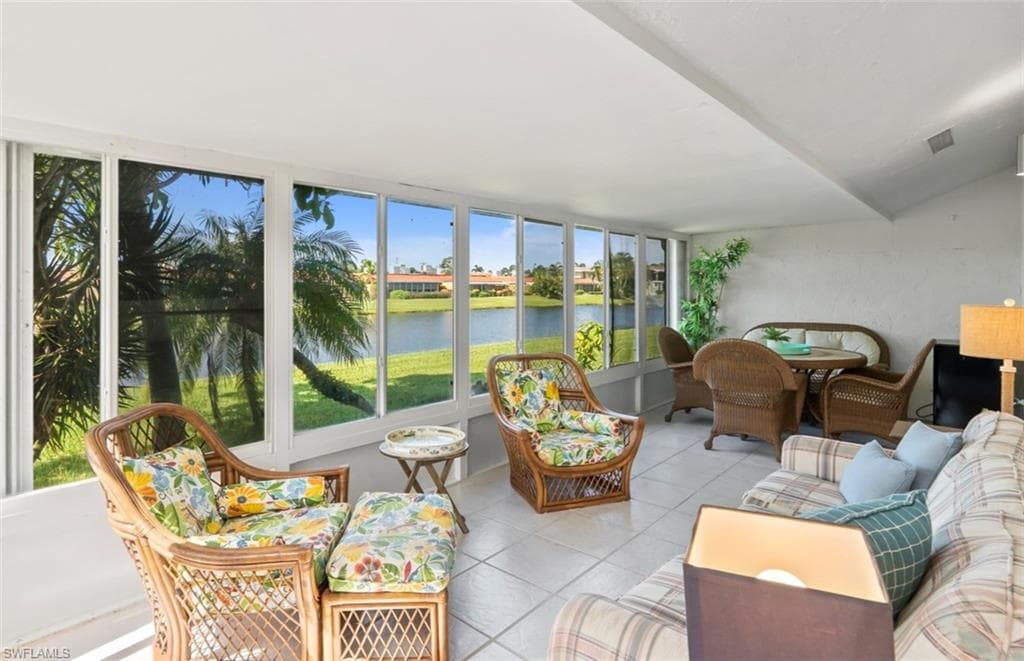 Spacious sunroom featuring a vaulted ceiling and a wall of windows