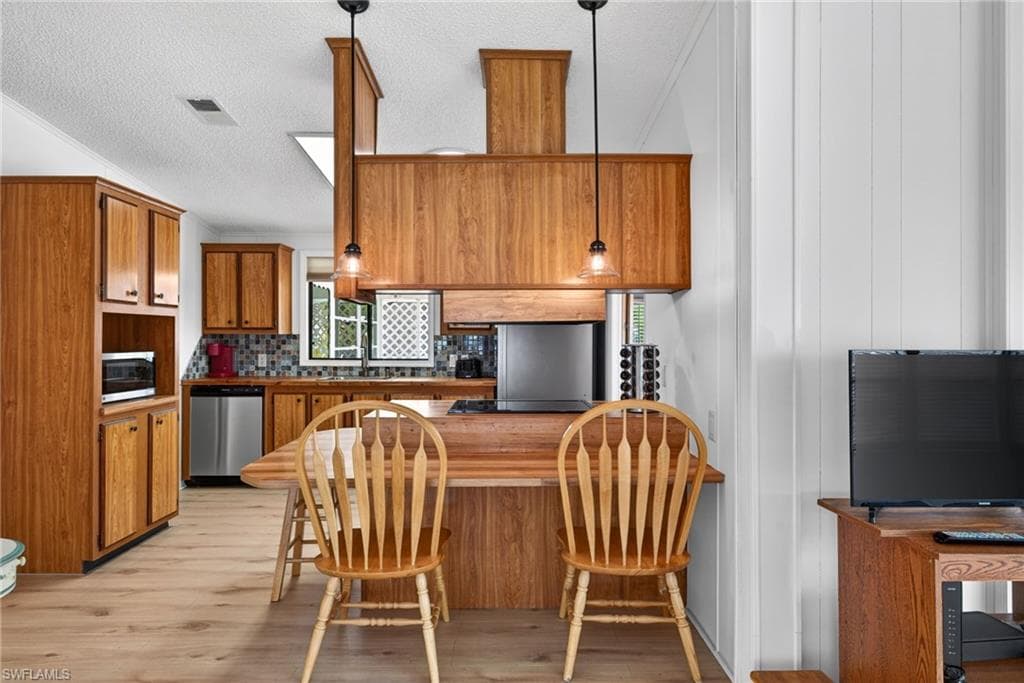 Kitchen area featuring wood-finish cabinetry, stainless steel appliances, and a mosaic tile backsplash