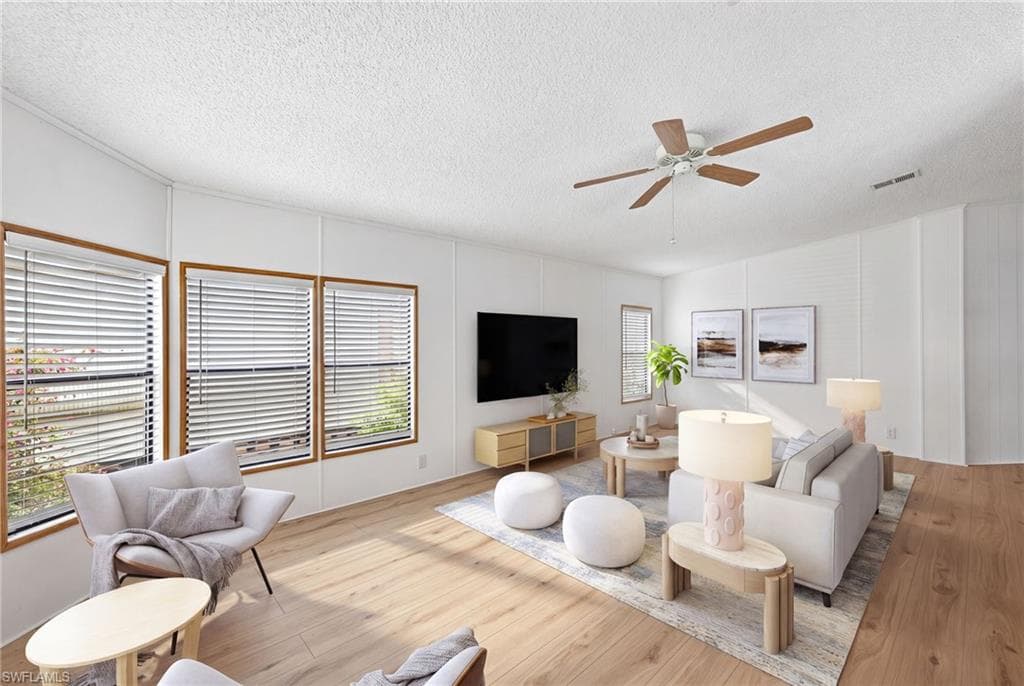 Virtually Staged Spacious room featuring wood-finish flooring, white walls, and multiple windows with blinds