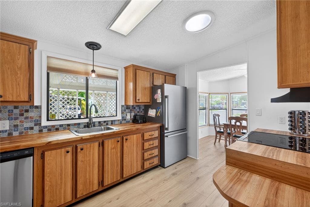 Kitchen featuring wood cabinetry, wood-finish countertops, stainless steel appliances, and wood-finish flooring