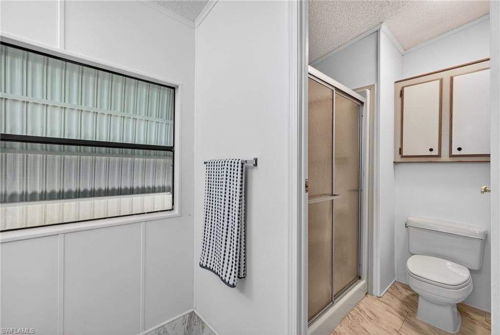Bathroom featuring a glass-enclosed shower, white toilet, and built-in upper cabinetry
