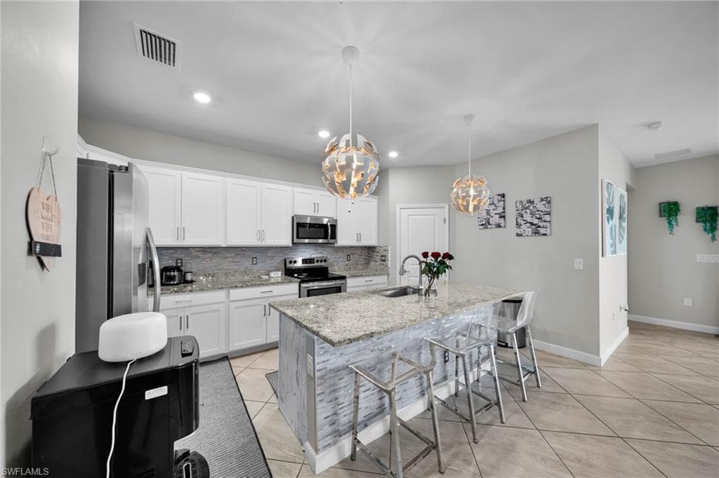 Kitchen with visible vents, a notable chandelier, appliances with stainless steel finishes, a sink, and light tile patterned floors