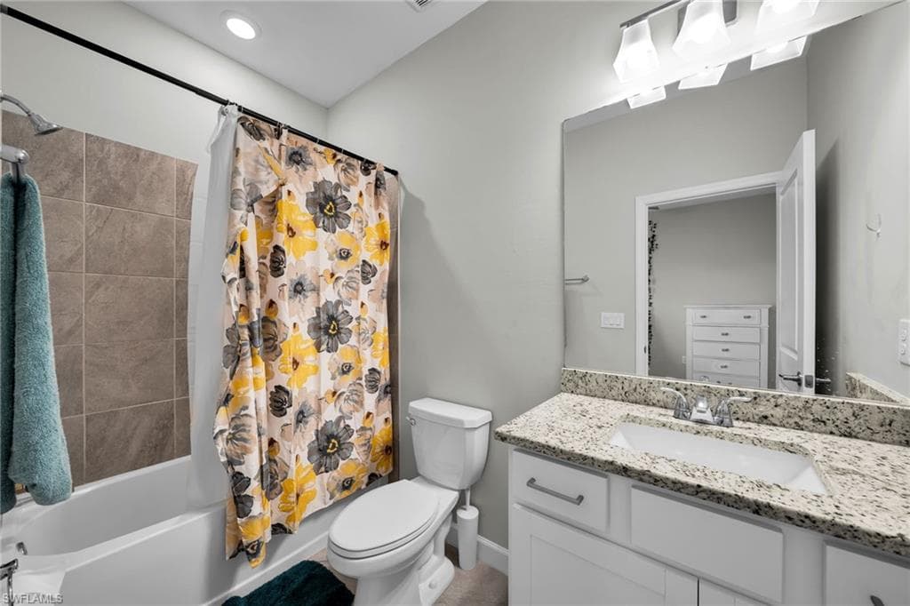 Bathroom with toilet, shower / bathtub combination with curtain, and vanity