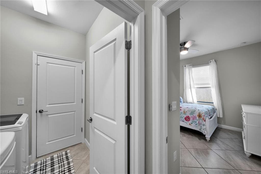 Laundry area with light tile patterned flooring, washing machine and dryer, laundry area, baseboards, and ceiling fan