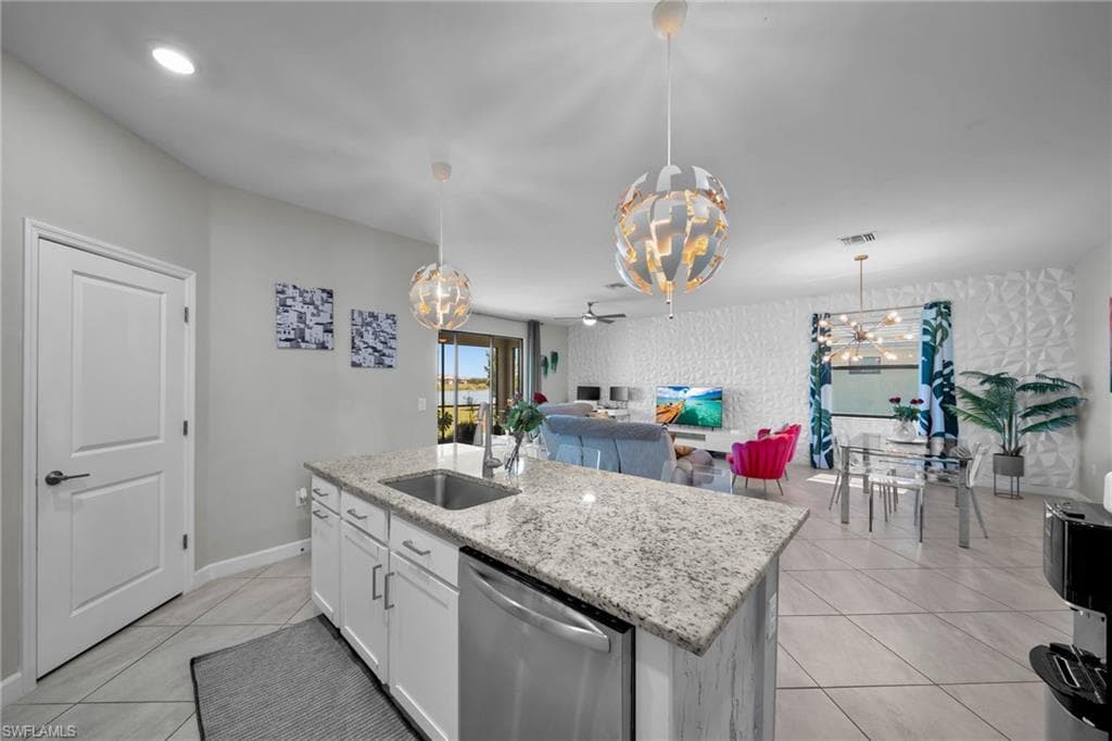 Kitchen with visible vents, a sink, open floor plan, stainless steel dishwasher, and light tile patterned floors