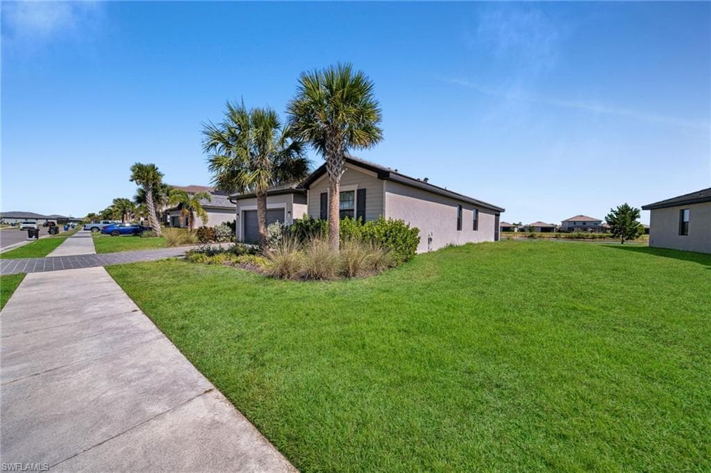 View of side of home featuring driveway, a yard, and an attached garage