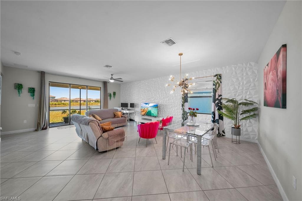 Tiled living room featuring ceiling fan with notable chandelier, baseboards, and visible vents