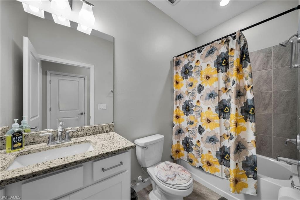 Bathroom with toilet, shower / bath combo, and vanity