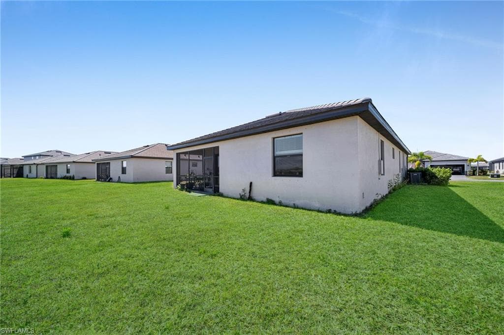 Back of house with stucco siding and a yard