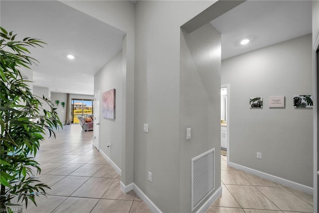 Hallway featuring light tile patterned floors, recessed lighting, baseboards, and visible vents