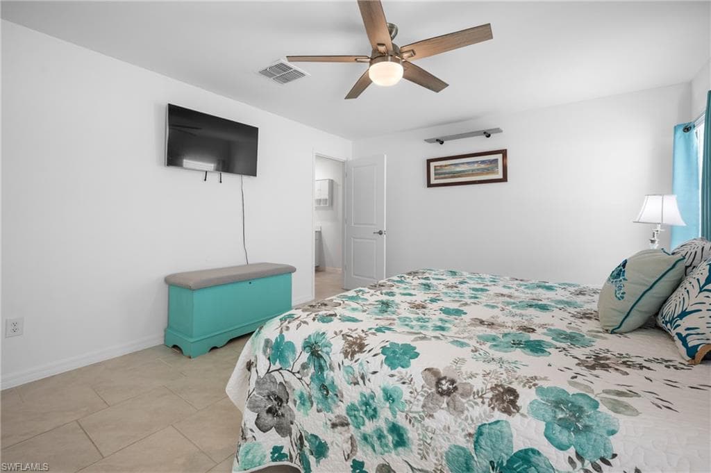 Bedroom featuring tile flooring, a ceiling fan with integrated lighting, and a white interior door