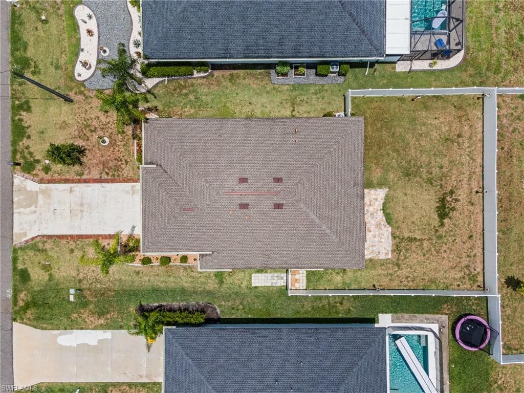 Aerial perspective of a property featuring a shingle roof and a concrete driveway