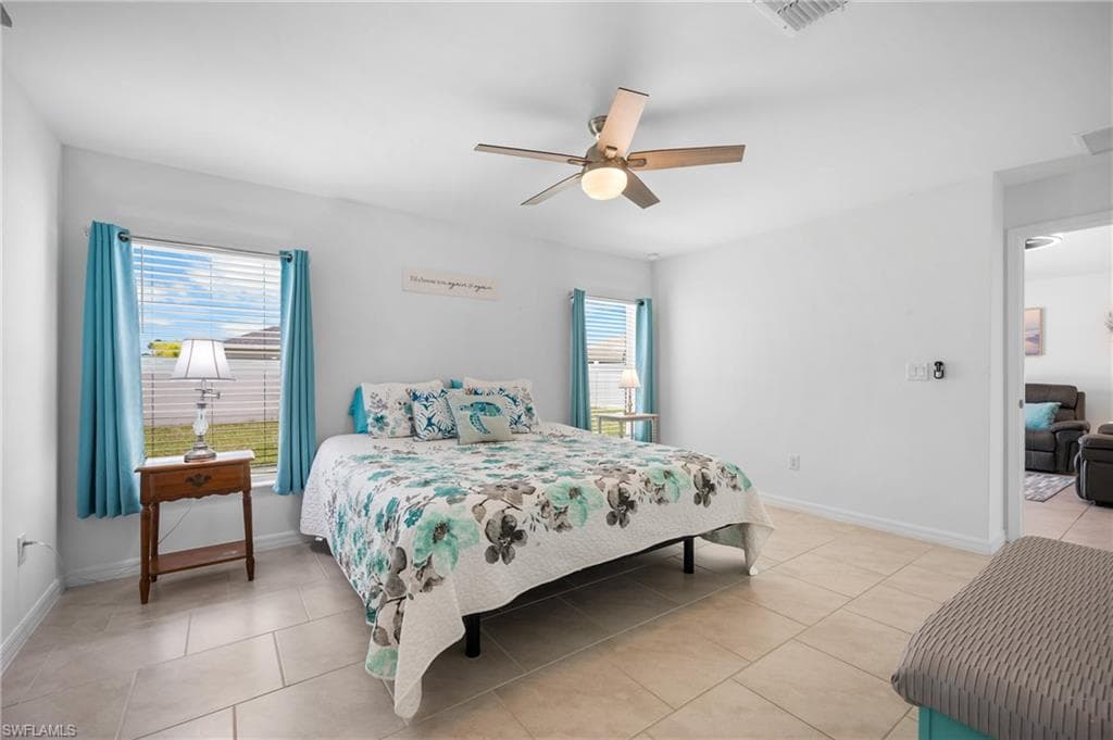 Spacious room featuring tile flooring, two windows with blinds, and a ceiling fan with integrated lighting