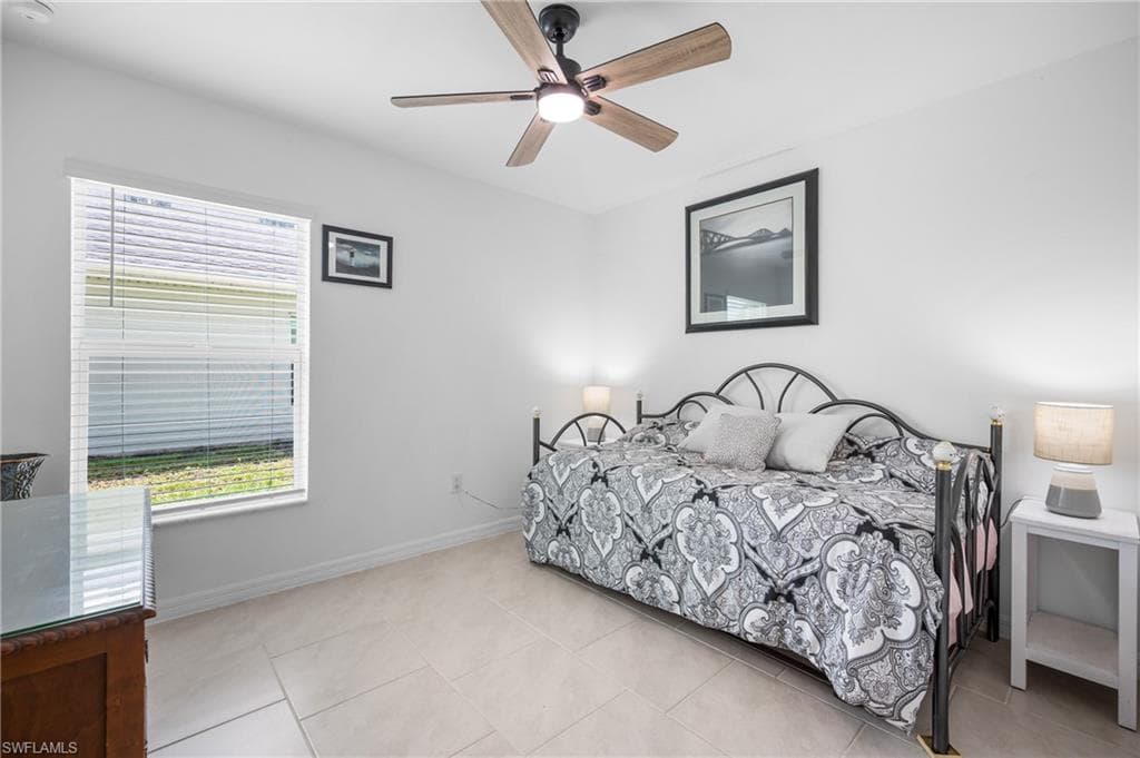 Bright room featuring light-toned tile flooring, a window with horizontal blinds, and a ceiling fan with integrated lighting